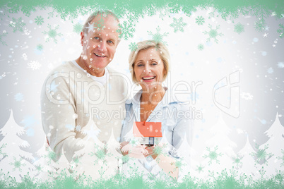 Happy mature couple with model house