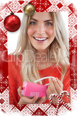 Composite image of cheerful woman discovering necklace in a gift