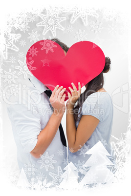 Composite image of couple covering their kiss with a heart