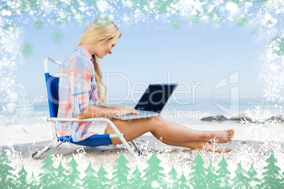 Woman sitting on beach using her laptop