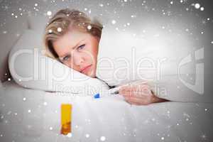 Composite image of sick blonde woman with a thermometer