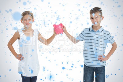 Brother and sister holding piggy bank together