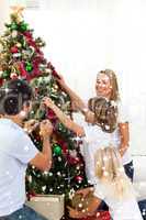 Composite image of joyful family decorating christmas tree