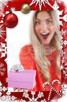 Composite image of astonished woman holding a gift