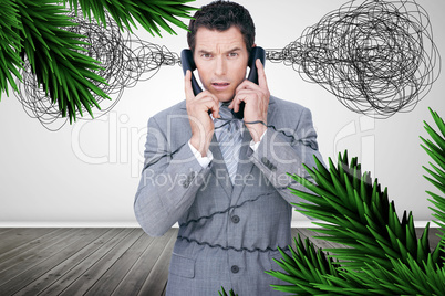 Overworked businessman holding two telephones