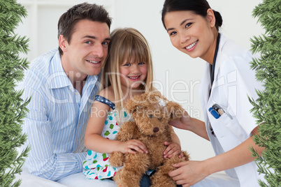 Portrait of a doctor and happy little girl examing a teddy bear