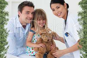 Portrait of a doctor and happy little girl examing a teddy bear