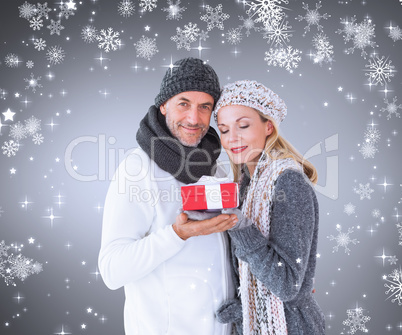 Composite image of happy winter couple with gift