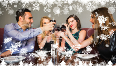 Composite image of happy friends drinking red wine in a bar