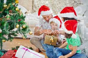 Composite image of family opening christmas gifts sitting on the