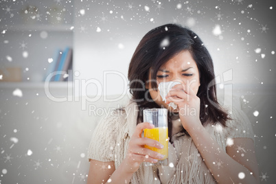 Composite image of sneezing woman drinking a glass of orange jui