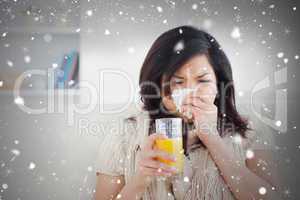 Composite image of sneezing woman drinking a glass of orange jui
