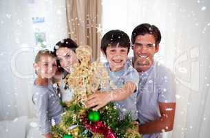 Happy little kid decorating a christmas tree with his family