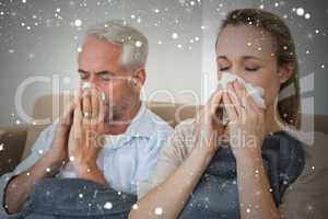 Composite image of sick couple blowing their noses sitting on th