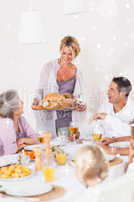 Composite image of mother bringing turkey to dinner table