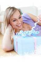 Composite image of cheerful blond woman holding a present lying