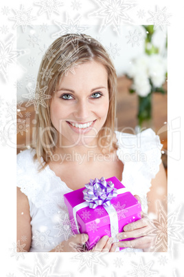 Charming young woman holding a present sitting on the floor