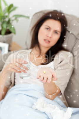 Sick woman taking her medicine on the sofa