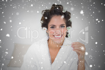 Composite image of smiling natural brunette holding thermometer
