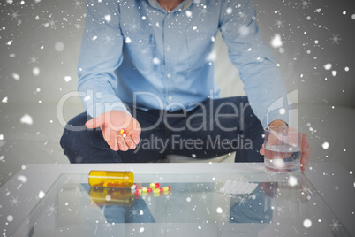 Composite image of casual man showing pills on open hand