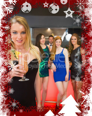 Beautiful blond woman holding cocktail standing in front of her