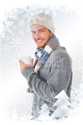 Composite image of handsome man in winter fashion holding mug