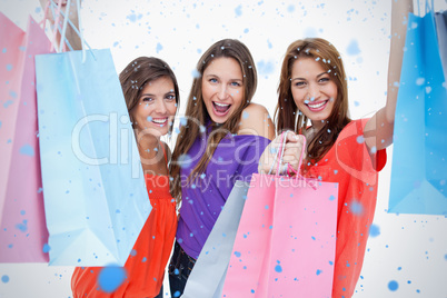 Three teenagers raising their arms while holding their purchases