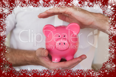 Composite image of casual businessman holding piggy bank