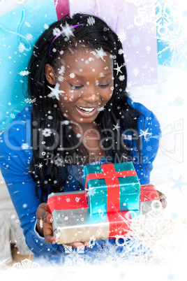 Smiling woman holding a present sitting on the floor