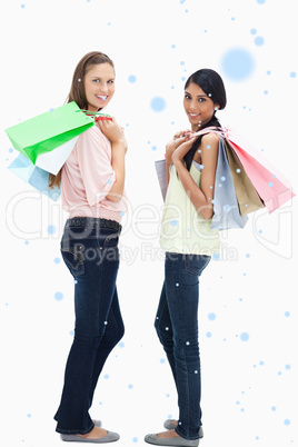 Composite image of smiling women carrying a lot of shopping bags
