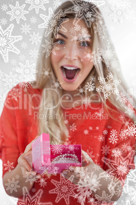 Composite image of surprised woman discovering necklace on a box
