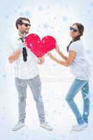 Hipster couple smiling at camera holding a heart