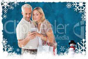 Composite image of happy couple with shopping bags and smartphon