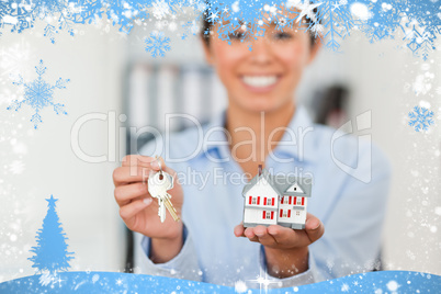 Attractive woman holding keys and a miniature house while lookin