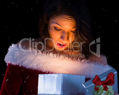 Composite image of pretty brunette in santa outfit opening gift