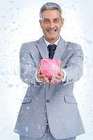 Composite image of joyful businessman holding piggy bank