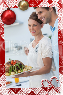 Cheerful couple showing roast chicken in the kitchen