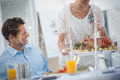 Smiling woman presenting a roast chicken during a dinner