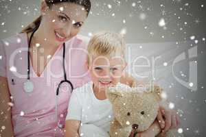 Smiling little boy holding a teddy bear on a hospital bed