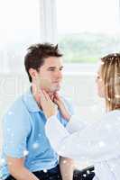 Female doctor examinating the throat of a happy patient sitting