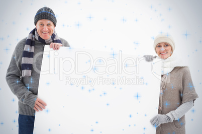 Mature couple in winter clothes holding card