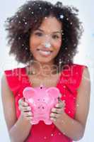 Composite image of piggy bank being held by a brunette woman