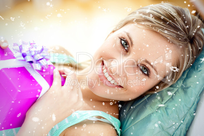 Composite image of cheerful woman holding a present