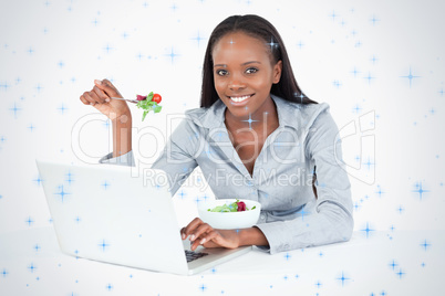 Businesswoman working with a notebook while eating a salad