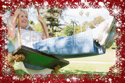Composite image of mature couple at swing in the park