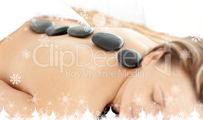 Composite image of relaxed woman with hot stones on her back
