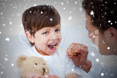 Composite image of young doctor taking little boys temperature