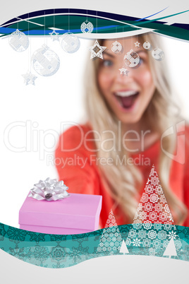 Composite image of astonished woman holding a gift