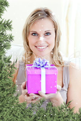 Handsome woman holding a present in a living room