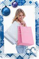 Woman looking back at the camera is carrying shopping bags over her shoulder
